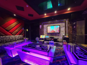 Phòng hát KTV 1127 Trần Hưng Đạo với bàn phát sáng màu tím và màn hình karaoke.